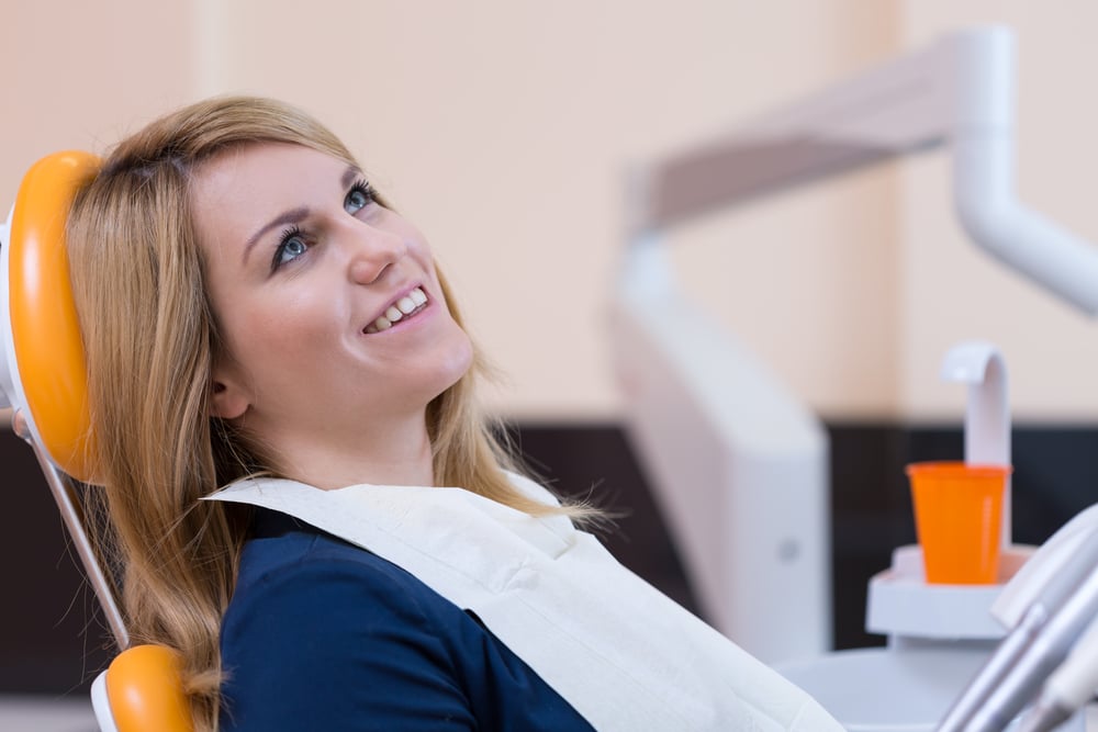 Calm female patient sitting in a dentist chair smiling