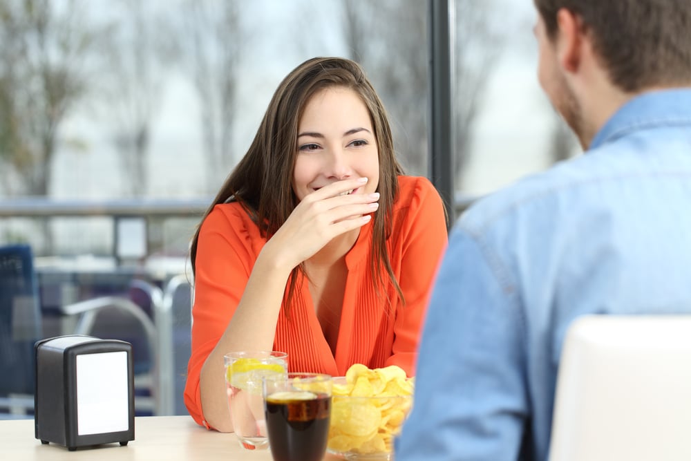 Female covering mouth due to bad breath