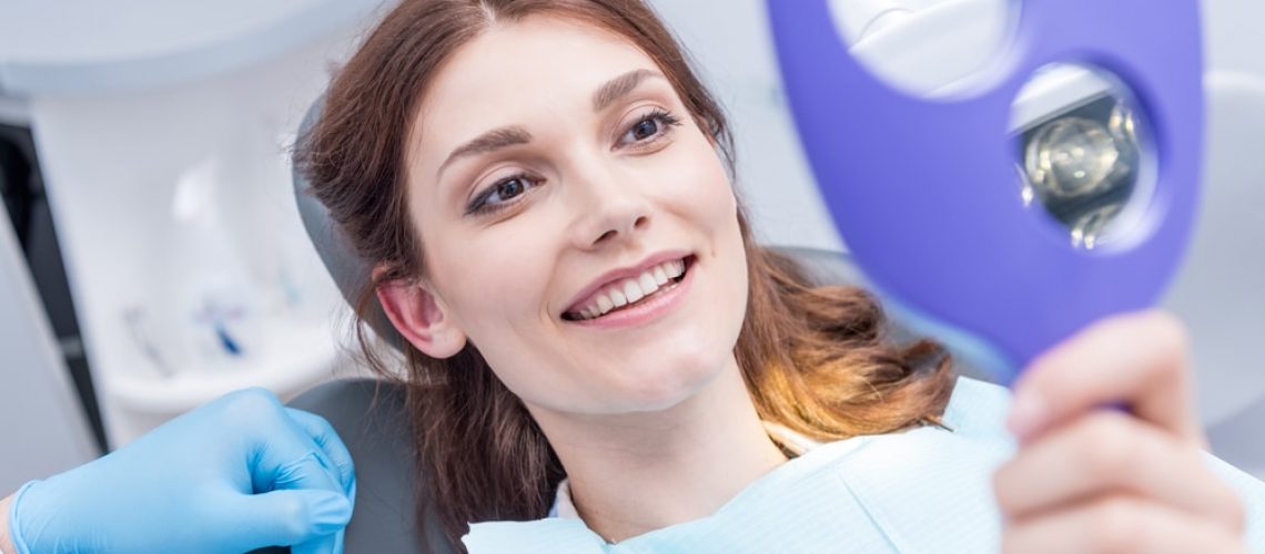 Smiling dental patient looking at her new smile in a mirror